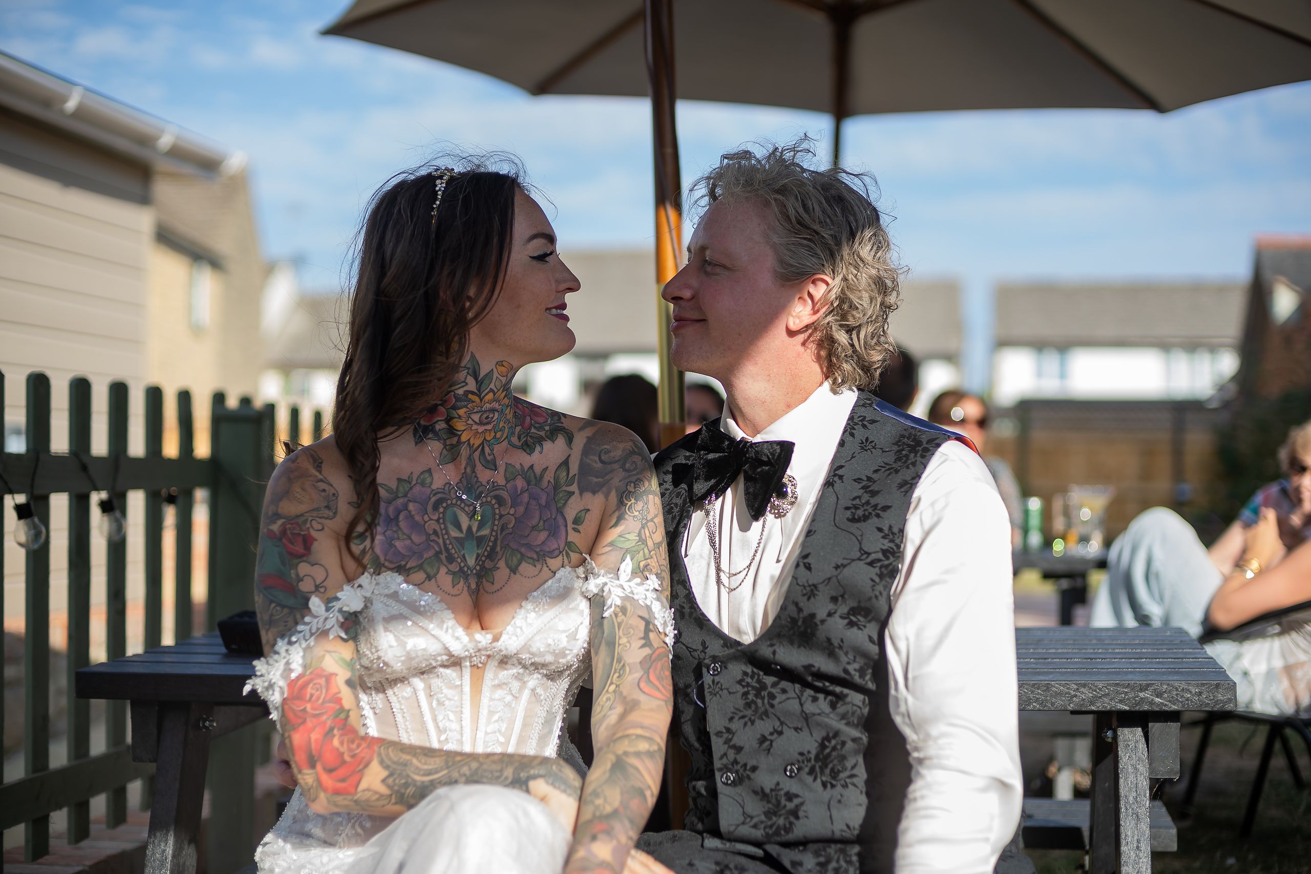 Brittany and Jay sitting together in the sun outside The Red Lion in Cricklade, drinks in hand on their wedding day